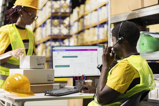 Customer support employee assisting clients in an industrial logistics hub, handling order mix up on e-commerce help line service. Black man resolving issues related to delivery delays. photo
