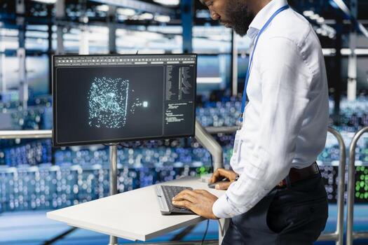 Black IT professional checking code at pc workstation in server farm, handling AI LLM visualization on elevated industrial platform. Engineer monitoring artificial intelligence systems. photo