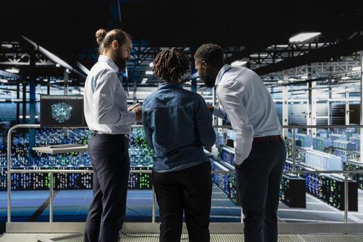 Data center system administrators using laptop to review AI LLM visualization. African american team of engineers use devices to analyze neural network outputs, ensuring stable operations. photo