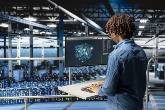 Black female IT specialist reviews AI performance data and LLM visualizations on computer workstation. Engineer overseeing neural network for server hub infrastructure operations. photo