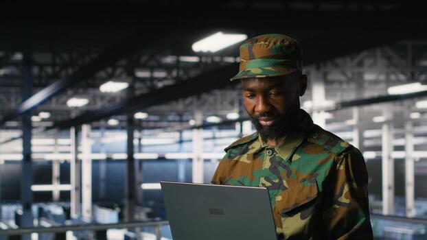 Army IT specialist in data center using laptop to defend networks against cyber threats. Military command center admin using notebook to identify potential intrusions or malicious activities photo