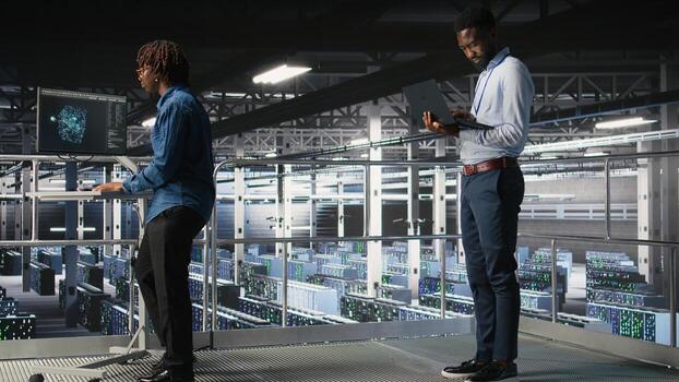 System administrators in data center using laptop to monitor neural network LLM visualization. Server hub teamworking colleagues overseeing rigs powering machine learning processes, photo