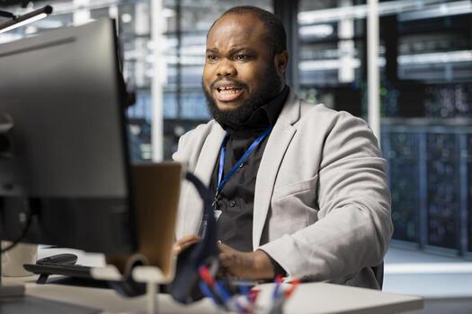 Scared programmer in server room panicked by diagnostic report showing critical hardware malfunction on PC. Afraid African american worker disturbed by error notifications risking system uptime photo