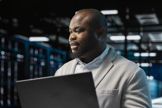 Close up of data center admin using laptop, reading malfunctions logs, doing checkup to prolong hardware life span. Server hub workplace employee monitoring infrastructure rigs, troubleshooting issues photo