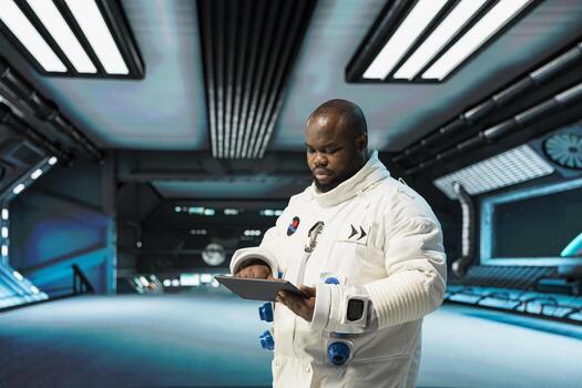 Astronaut troubleshooting spacecraft hardware systems using device. African american man in spaceship analyzing mission logs on tablet during planetary exploration flight photo