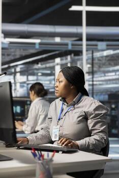 Data center software developer running diagnostic scripts, examining infrastructure. African american server room IT expert using PC to evaluate performance metrics, maintaining system stability photo