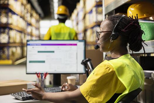 E-commerce support worker responding to problems like lost parcels or order tracking, surrounded by cargo boxes on racks in a fulfillment center. Call center operations on headset. photo