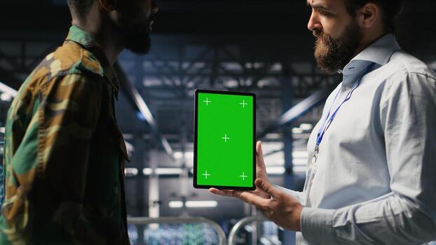 Military personnel overseeing AI computing operations on isolated screen tablet in high tech server facility. Army tech experts using chroma key device to oversee communication systems photo