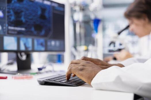 Close up of lab technician typing on PC keyboard, looking at 3D molecular model. Nanotechnology Researcher using bioengineering program on PC in medical lab displaying DNA data photo