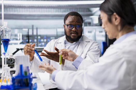 Teamworking lab colleagues inspecting liquids in test tube, looking for breakthroughs during clinical trials. Team of experts doing brainstorming, comparing chemicals vials, testing right formula photo