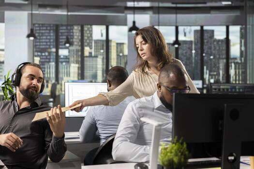 Workplace support person offers documents to colleagues in office, carrying archived files and folders with a moving cart. Assisting in task completion and business intel, projections. photo