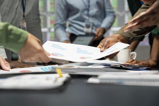 Close up of diverse specialists evaluating data numbers on archived files, exchanging reports and insights to establish clear enterprise objectives in a quiet strategy room late at night. photo