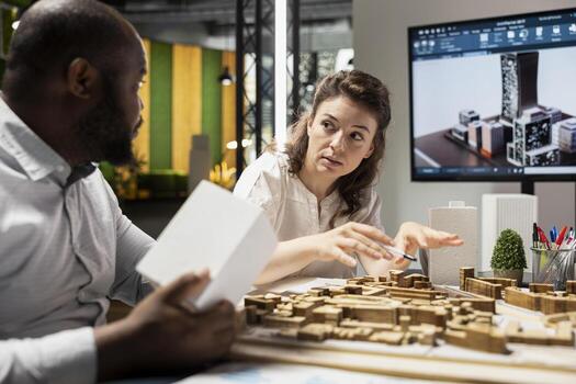 Multiethnic group of developers and contractors discussing urban housing models and blueprints layout revisions for an upcoming residential development project. Smart city planning session. photo