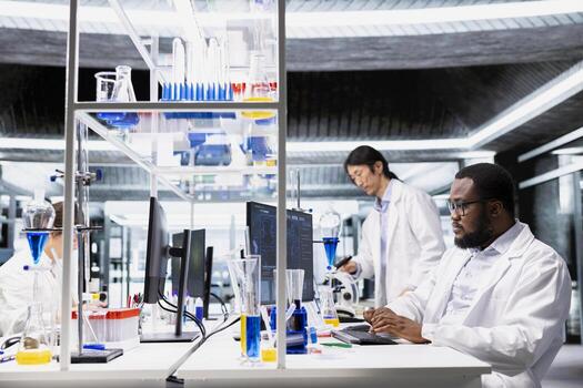 Molecular biologist uses computer program displaying DNA data analysis interface in laboratory. African american man using bioinformatics genomics software on PC in sterile lab environment photo