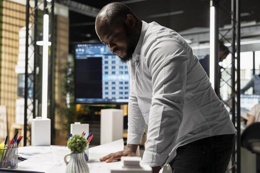 African american property developer focusing on land acquisition and construction planning while reviewing project layout that align with smart city and infrastructure growth. innovation hub. photo