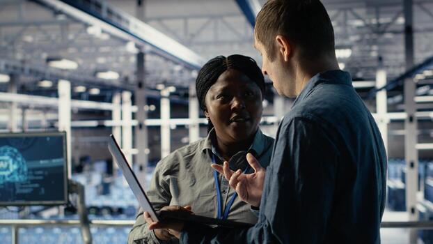 Team of data center engineers investigate neural networks configuration, making adjustments. Teamworking server hub coworkers use notebook to check deep learning errors, camera B photo