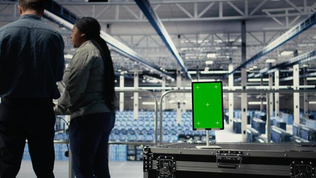 Green screen tablet in server room in front of admins optimizing deep learning systems handling tasks. Mockup device used by data center workers adjusting AI model parameters, camera A photo
