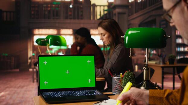 Focused senior man reading academic text with chroma key on pc at the university, sitting in vintage study area and browsing online coursework. Knowledge and ambition. photo