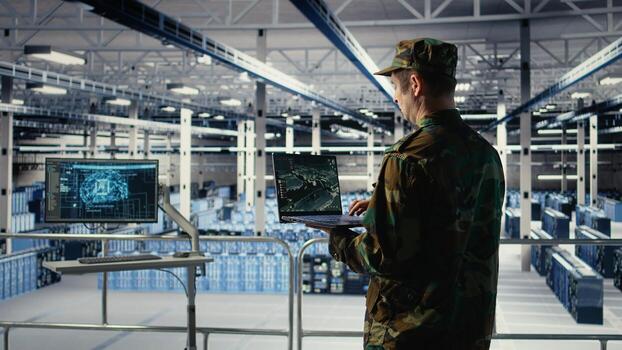 Military engineer in data center tracking satellite coordinates using laptop interface. Soldier in server room analyzing reconnaissance data through satellite imaging systems, camera A photo