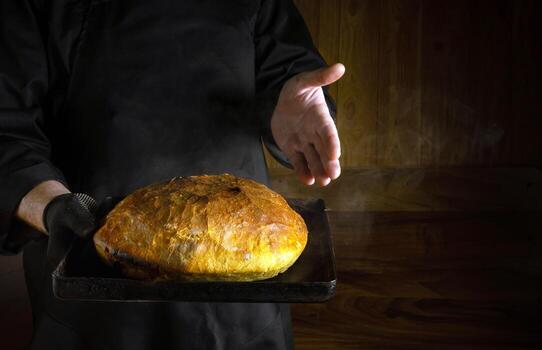 The baker presents freshly baked wheat bread in the bakery. Place for advertising. The concept of baking bread at home photo