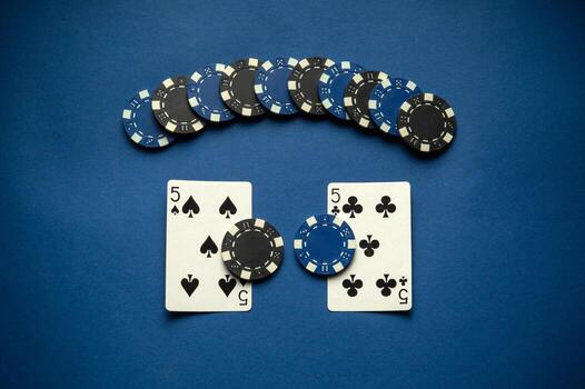 A card game setup showcases two five cards flanked by several poker chips. The blue background adds contrast to the game elements, making them stand out in the evening atmosphere photo