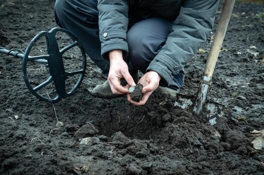 The coin is a lucky find with a metal detector in the field. Silhouette of a man while searching for a treasure in nature. photo