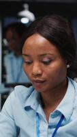 Vertical Black female works on researching and documenting reports after hours, data updates and business enterprise, after hours work in a dark office. Finance targets and project development. Camera B. video