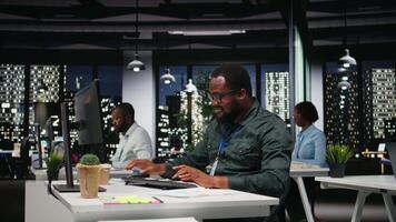 negro masculino tutor documentando números y Finanzas métrica después horas, investigando actualizaciones y organizando el agenda para negocio gestión. chico ajuste objetivos y objetivos cámara una. video