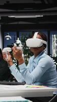vertikal kvinna kontor arbetstagare använder sig av vr headsetet med artificiell intelligens efter timmar, arbetssätt hård med virtuell verklighet till säkerställa uppgifter komplettering och prognostisering projektioner. 3d simulering. kamera a. video