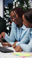 Vertical Black business people working together on report writing in dark office, collaborating on building a new development strategy after hours. Reviewing insights to enhance efficiency. Camera B. video