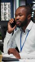vertikal manlig anställd svar telefon ring upp för en avlägsen diskussion med kollega, leende under en samarbete chatt på telefon linje. anpassningsförmåga till samordna en ny projekt sent på natt. kamera b. video