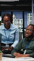 vertikal afrikansk amerikan analytiker samarbetande på en projekt med finansiell prognoser, utskjutande data till bygga ut de företag aktivitet och vinst. lagarbete i arbetsyta till säkerställa mål. kamera b. video