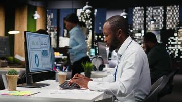 negro negocio consultor corrección de pruebas financiero números a escritorio después horas, estudiando datos para mensual actuación informes. asegurando empresa objetivos logro a noche. cámara b. video