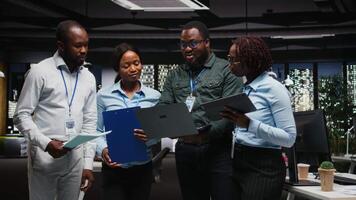 porträtt av svart arbetare samarbetande på projekt strategi och genomgång, använder sig av data från diagram på gadgetar till kör prestanda metrik. främja lagarbete och en arbetsplats partnerskap. kamera a. video