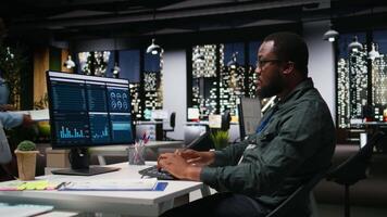 manlig kontor arbetstagare använder sig av data och teknologi för företag förvaltning, granskning påstående grafer på övervaka till skapa rapporter och förbättra effektivitet, mål prestation. syn. kamera a. video