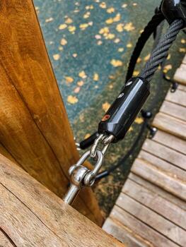 Here is a detailed closeup image of a sturdy rope that is securely attached to a solid wooden post, which could be utilized for various purposes including climbing and securing items photo