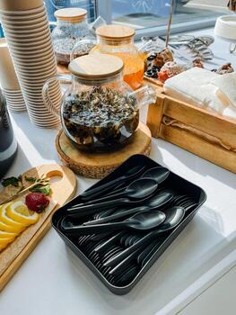 On the table, there is a tray that contains a selection of plastic spoons and forks neatly arranged for convenience. It serves as the perfect tableware for any meal or gathering photo