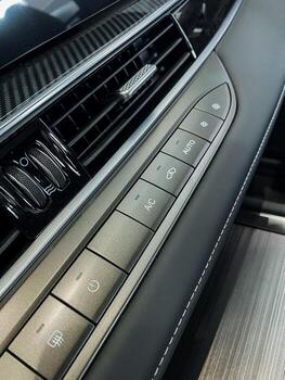 This image shows a closeup of a car dashboard, featuring an array of buttons, intricate air vents, and possibly highend materials, emphasizing its luxurious design and technology photo