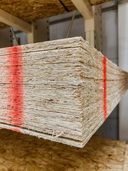 A large stack of plywood sheets is suspended from a sturdy rack in a spacious warehouse, ready for use in various construction projects and woodworking tasks within the facility photo