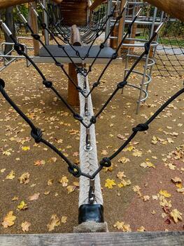A vibrant playground filled with various ropes sprawled across the area, and colorful leaves scattered on the ground, creating a fun and adventurous atmosphere for children to enjoy photo