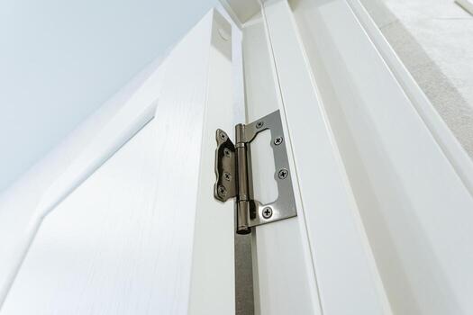 This is a detailed closeup view of a door hinge attached to a pristine white door, showcasing the intricate design and functionality of household hardware beyond just the hinge itself photo