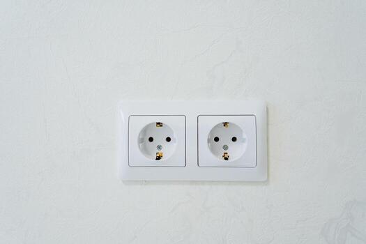 On a pristine white wall, there are two neatly installed white electrical outlets that provide convenient access to power. They serve as essential electrical connectors for various devices photo