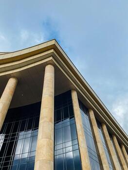 An impressive and large structure featuring numerous columns, set against a clear blue sky that complements its grandeur and design, which adds to the visual appeal of the building photo