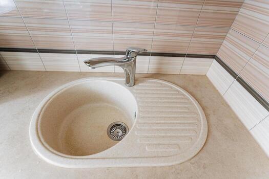 This modern kitchen sink features an elegantly designed faucet that adds sophistication and a practical integrated drainboard, enhancing both functionality and style in your kitchen photo