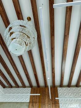 Experience the Stylish Modern Ceiling View adorned with an Elegant Chandelier complemented by Decorative Beams, creating a truly sophisticated atmosphere in any room or space. Perfect for renovations photo