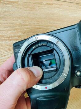 This image features a hand gripping a camera that displays its open lens, highlighting the intricate details involved in photography equipment inspection, essential for achieving the best results photo