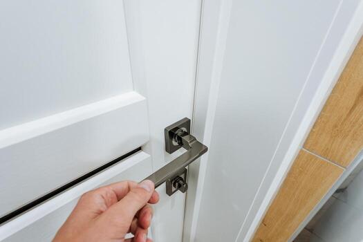 A person is meticulously and thoughtfully opening a pristine and immaculate white door by skillfully inserting a key that fits perfectly and seamlessly into the complex lock mechanism photo