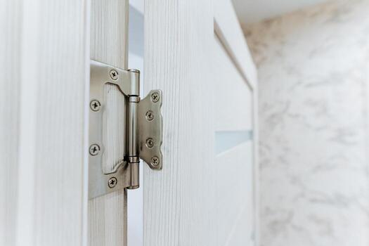 This image features a closeup view of a modern door hinge set within a beautifully bright interior environment, showcasing the details and design in a sophisticated and minimalistic manner photo