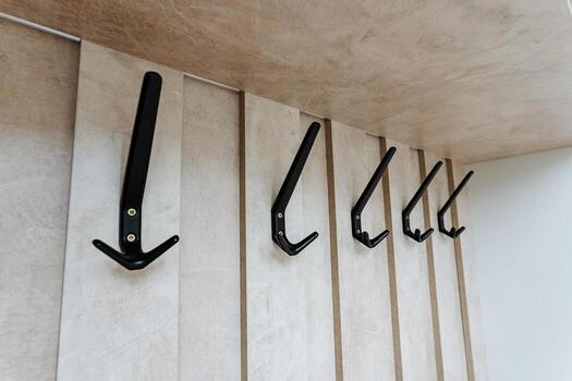 The stylish black wall hooks, set against a minimalist wooden background, enhance their elegant design and functionality, merging the perfect balance of style with practical utility for any space photo