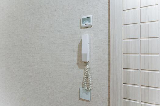 wallmounted intercom, wallmounted intercom handset with textured surface and coiled cord, wallmounted intercom device featuring coiled cord and textured surface for ease of use photo